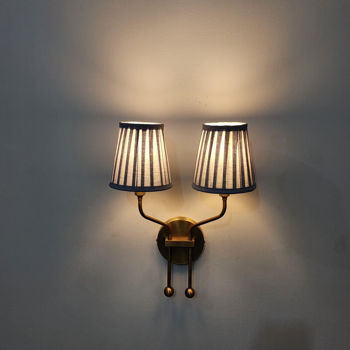 Brass vintage wall sconce with pleated double shades.