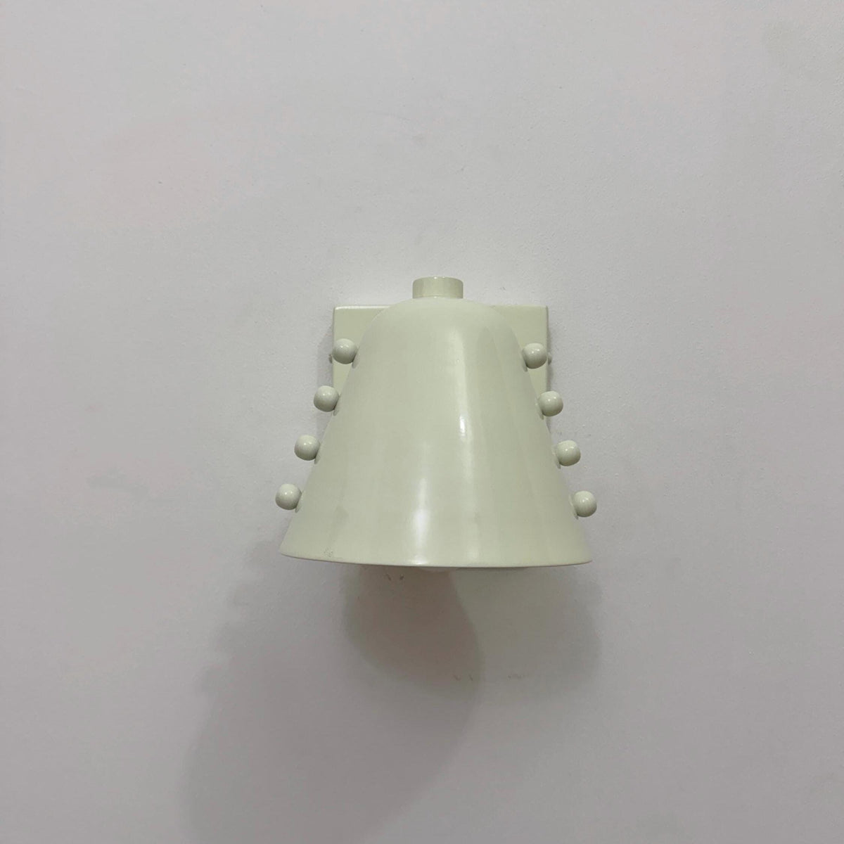 Brass wall light with white cone shade, minimal design. Ember Lighting
