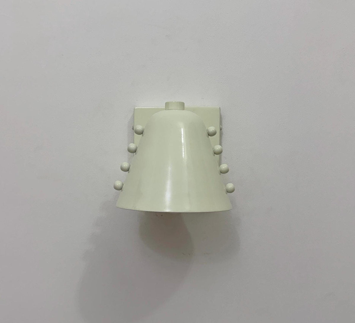 Contemporary brass wall light featuring a white cone shade. Ember Lighting