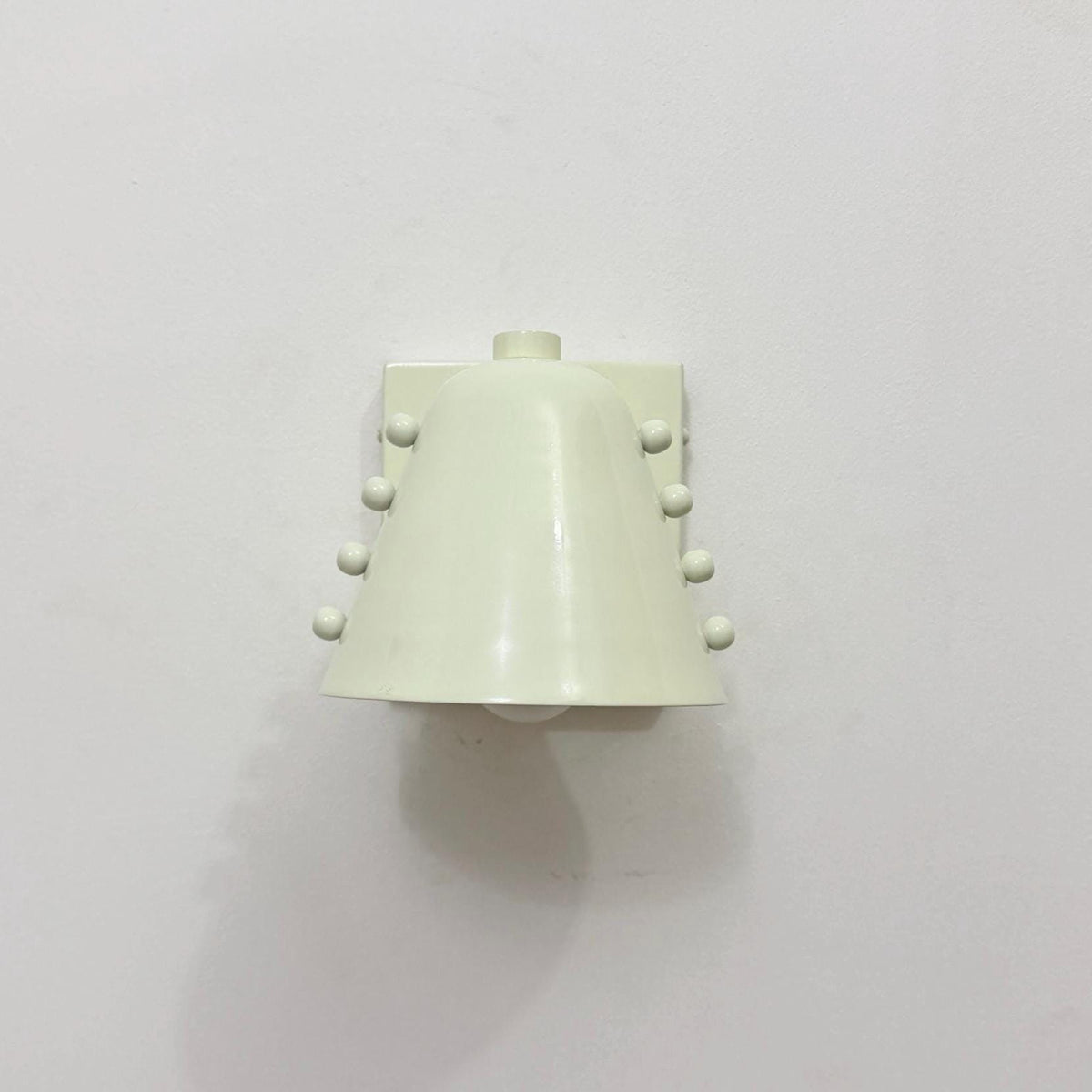 Elegant brass wall light fixture featuring white cone shade. Ember Lighting