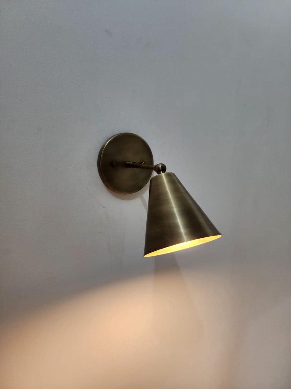 Elegant vintage brass adjustable wall sconce with cone shade.