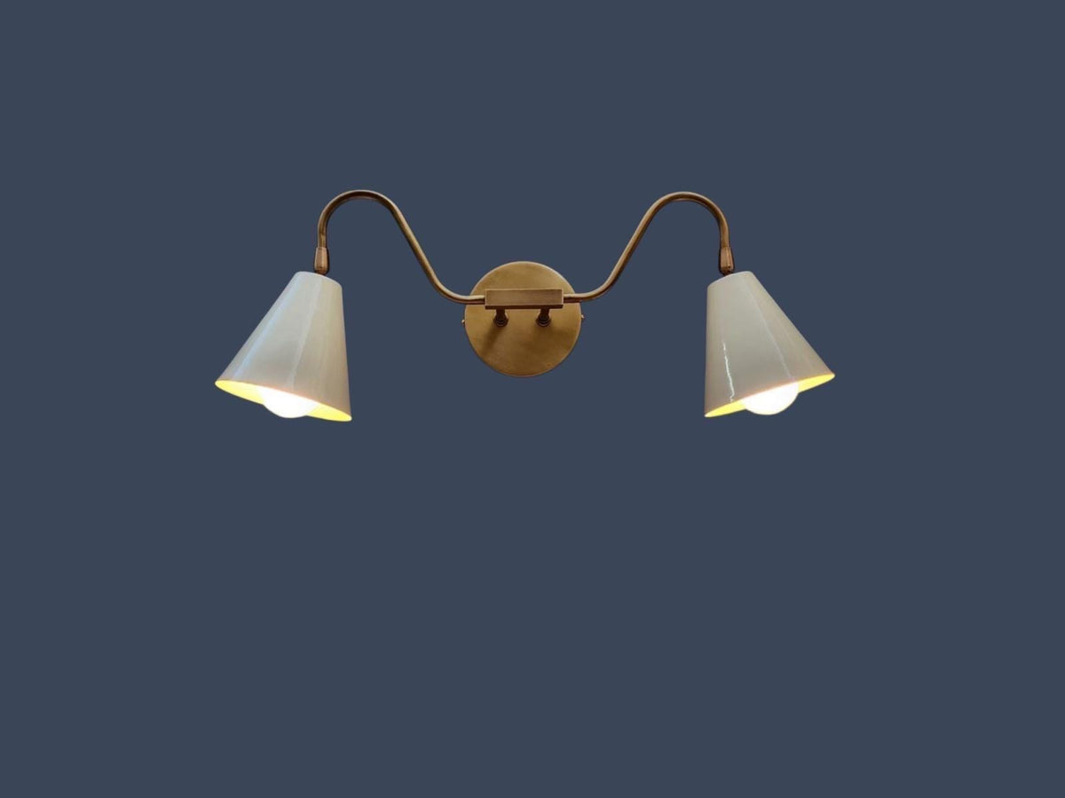Handmade brass lighting in double arm wall sconce design. Ember Lighting