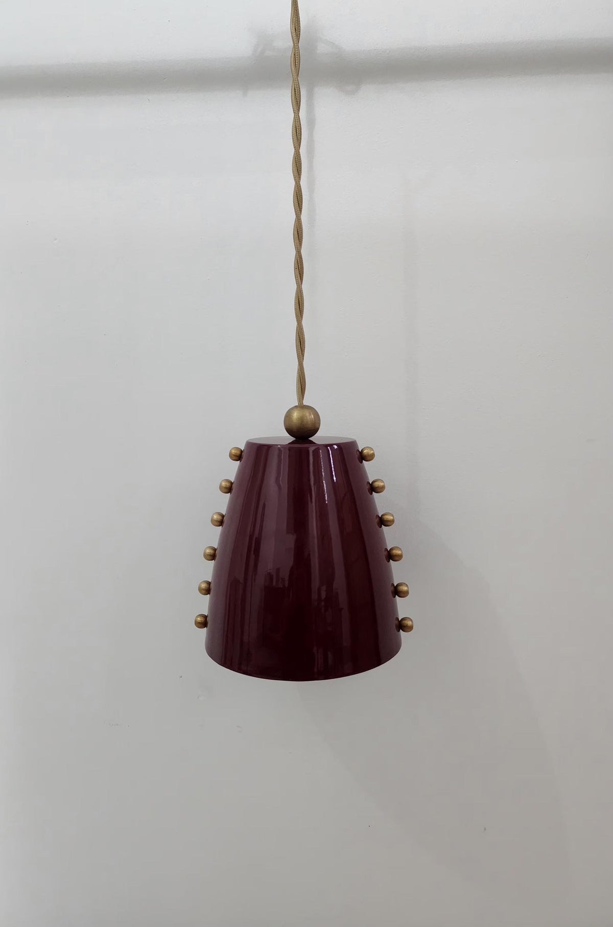Mid-century raw brass pendant light with cone shade. Ember Lighting