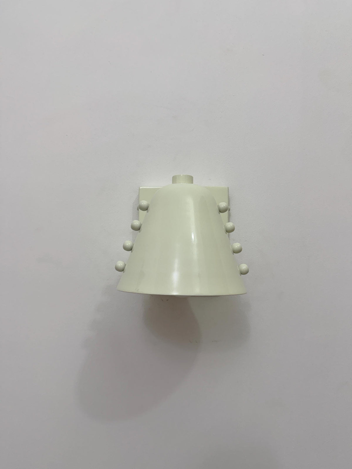 Minimalist brass wall light with white cone shade design. Ember Lighting