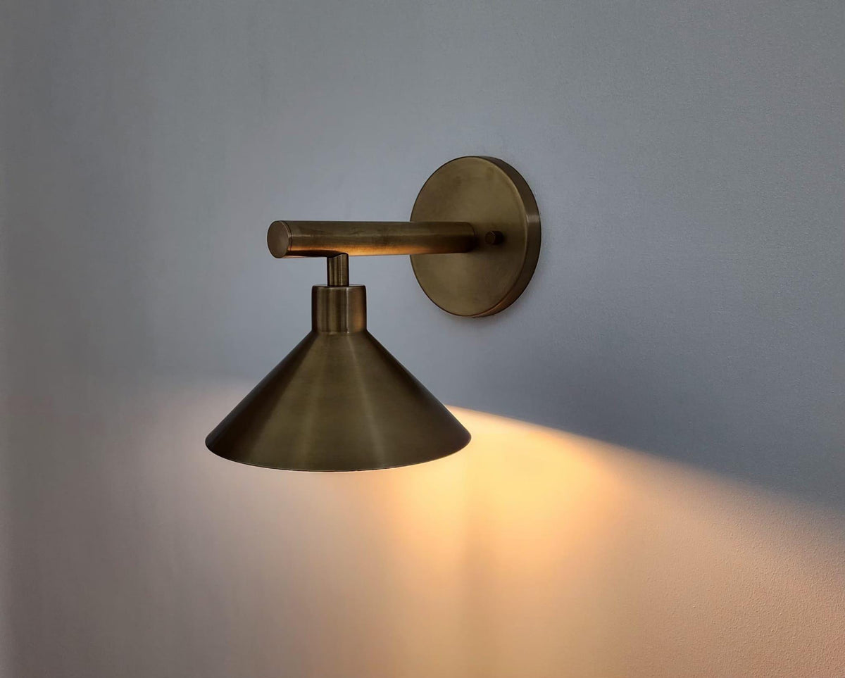 Modern brass wall sconce with cone shade.