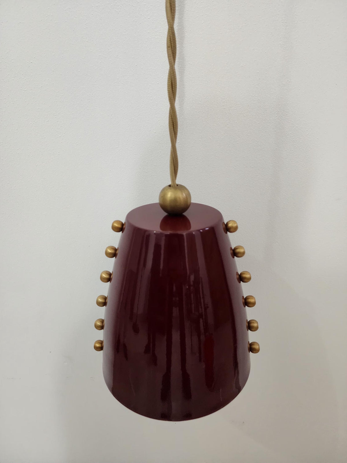 Raw brass mid-century pendant light featuring cone shade. Ember Lighting