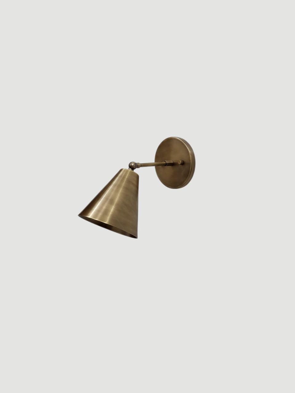 Vintage brass adjustable wall sconce featuring a cone light.