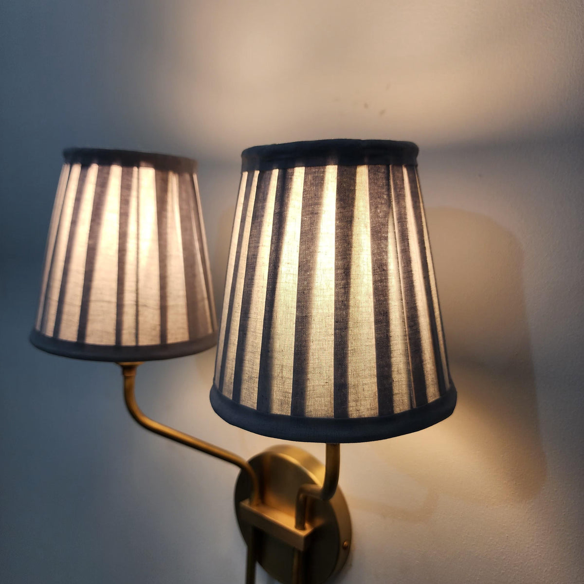 Vintage brass wall light with double pleated lampshades.