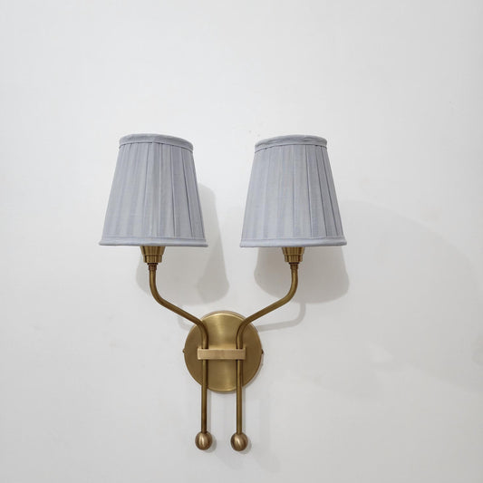 Vintage brass wall sconce with two pleated lampshades.